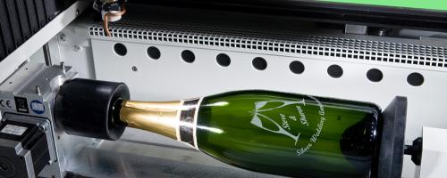 Gravação de garrafa de champanhe montada em um eixo rotativo dentro de uma máquina a laser de CO2
